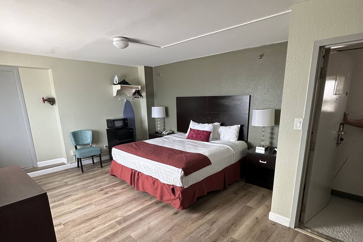 Una habitación de hotel con una cama grande, piso de madera, un escritorio y una silla.