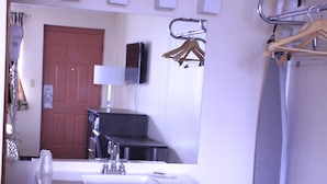 Une salle de bain équipée d’un lavabo, d’un miroir, de placards et d’un rideau de douche.