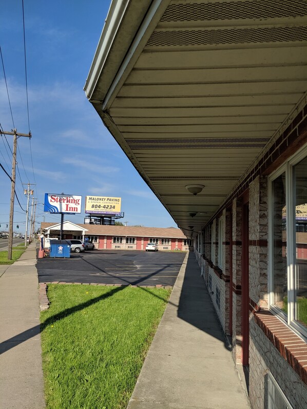 Un motel con galería techada, estacionamiento y carteles de Sterling Inn y Maloney Paving.