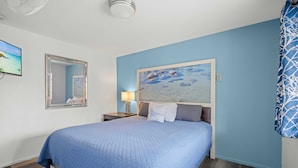 Una camera da letto con un letto, un comodino, una lampada, uno specchio e un quadro appeso al muro.