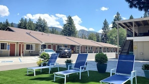 Un motel con parcheggio, area salotto esterna e montagne sullo sfondo.