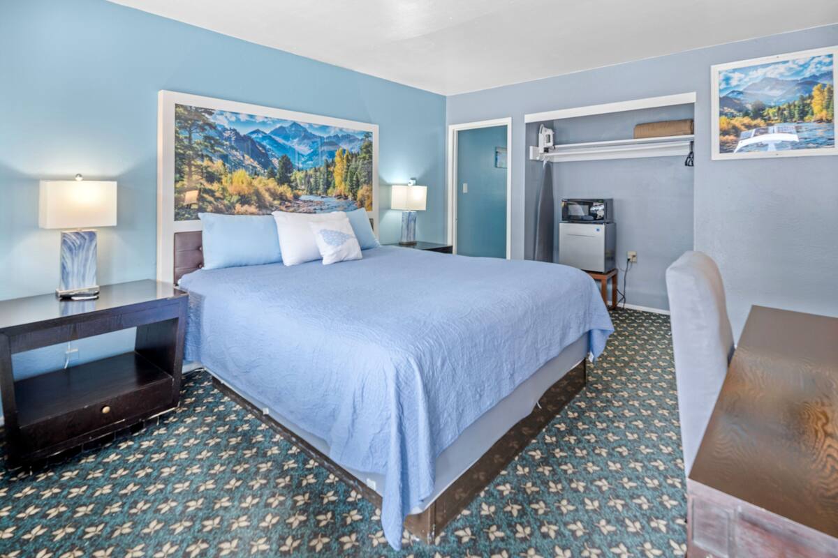 A bedroom with a bed, two bedside tables, a nightstand, a desk, a chair, and a small table.