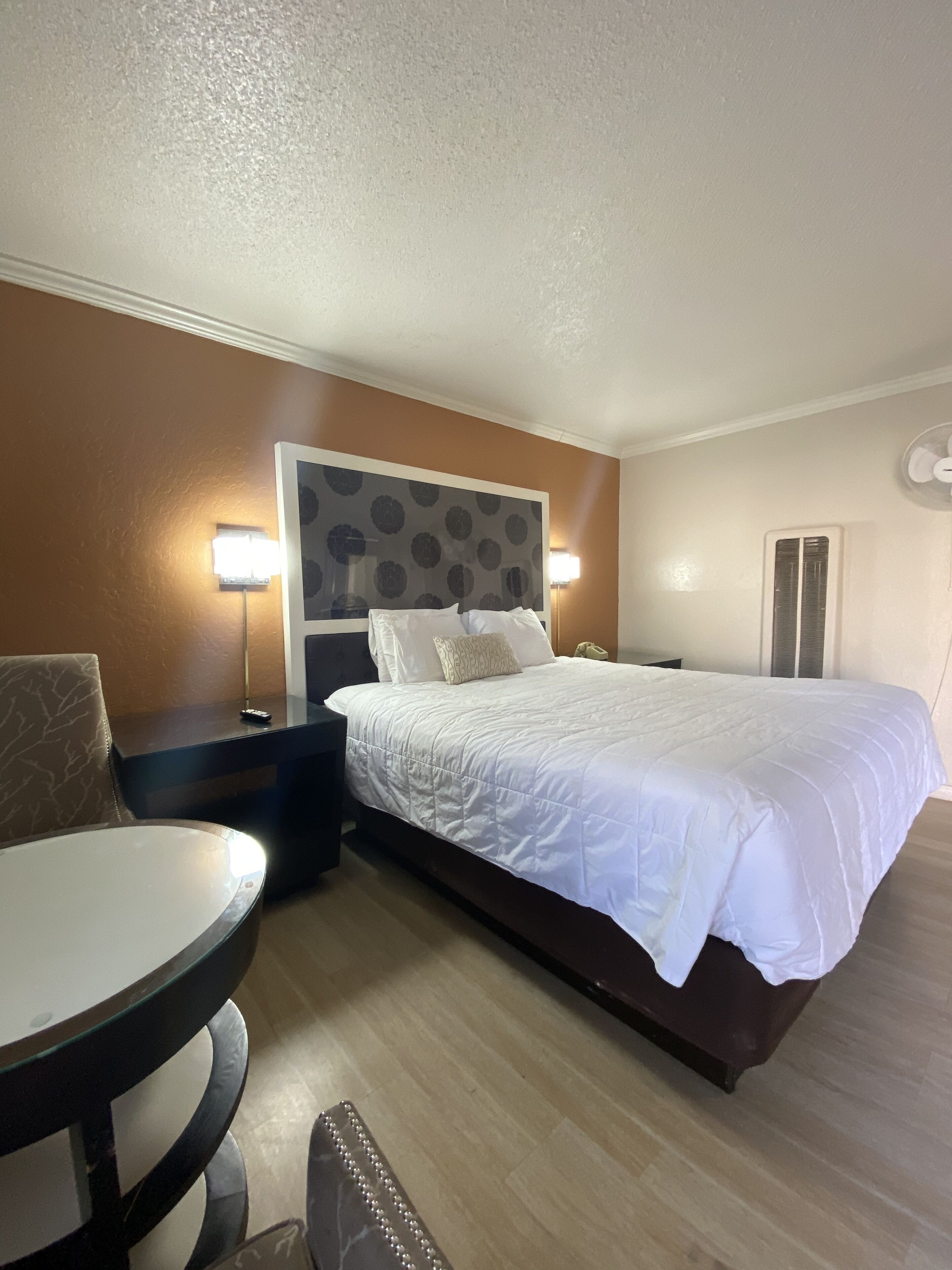 A hotel room with a bed, bedside tables, a round table, and a chair.