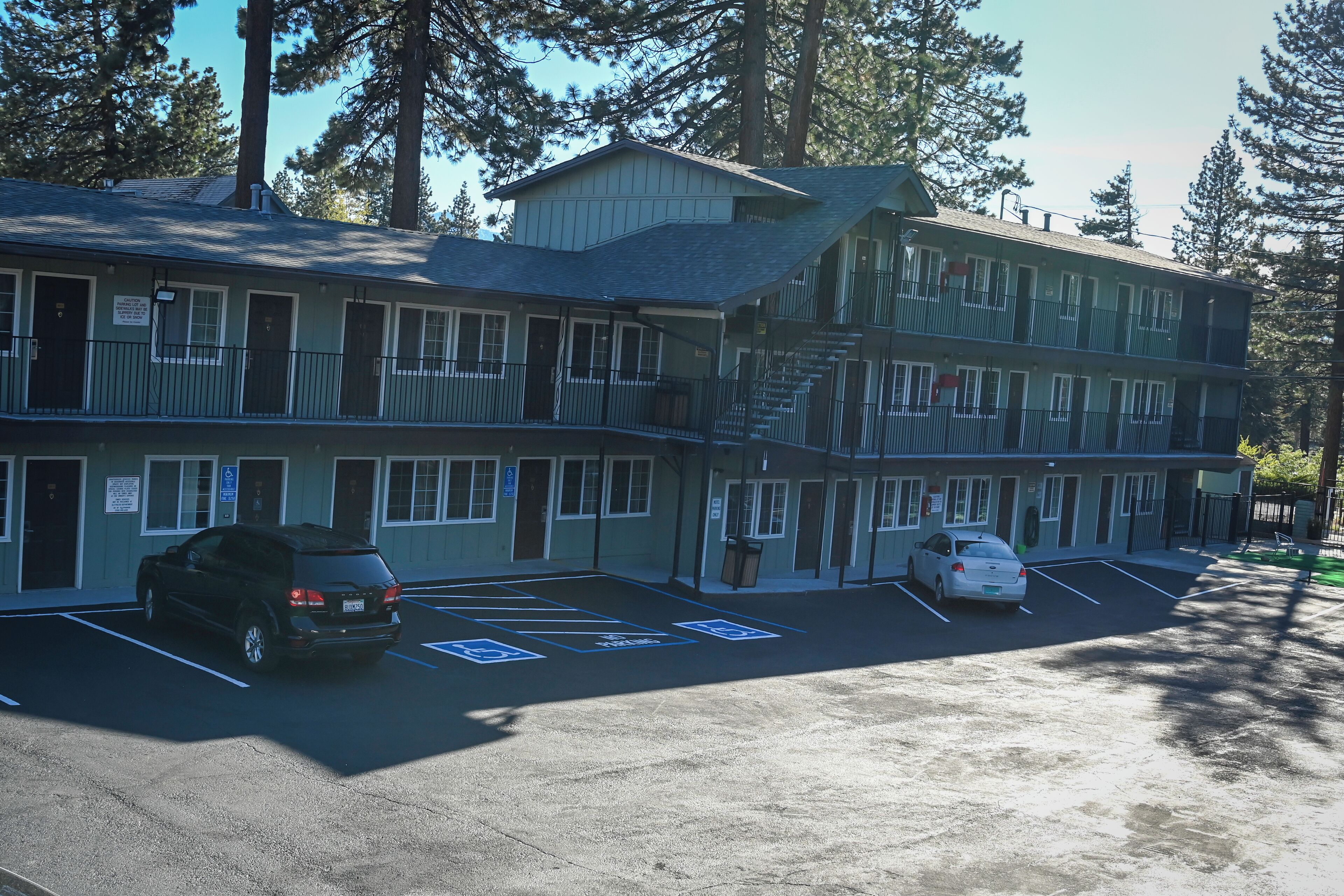 A motel with a two-story structure, a parking lot with handicapped accessible spaces, and a sign indicating no smoking.
