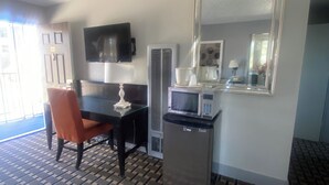 Une chambre d’hôtel équipée d’une table à manger, d’un four à micro-ondes, d’un réfrigérateur, d’un téléviseur fixé au mur et d’un sol à motifs.