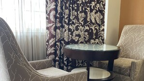 Une pièce comprenant deux fauteuils et une petite table ronde, ainsi qu’un rideau et un tapis à motifs.