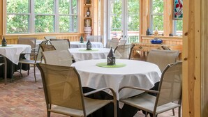 Ein Essbereich mit Tischen und Stühlen, Holzwänden und großen Fenstern.