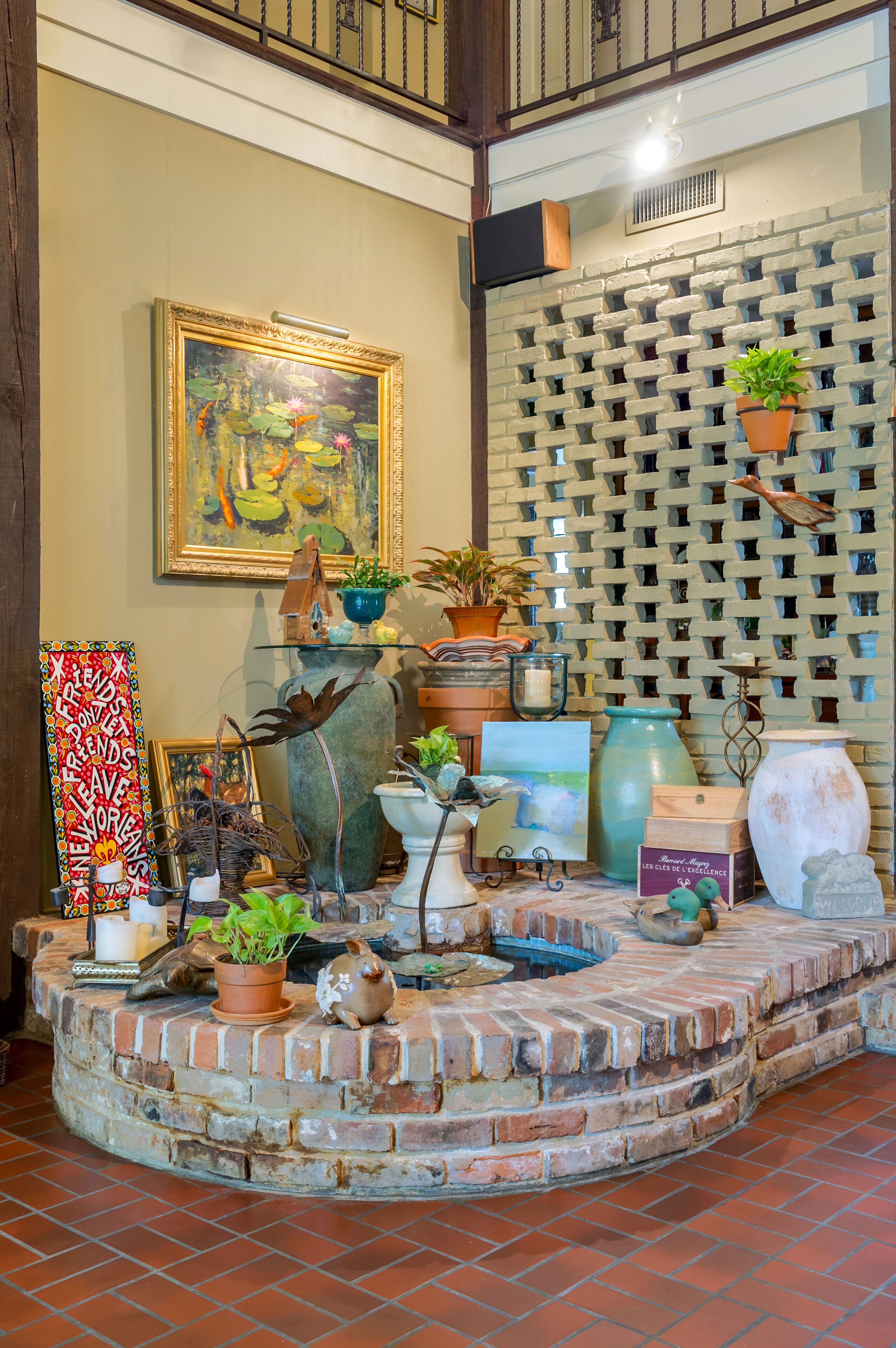 A cozy indoor space with a brick fireplace, various potted plants, and a framed painting on the wall.