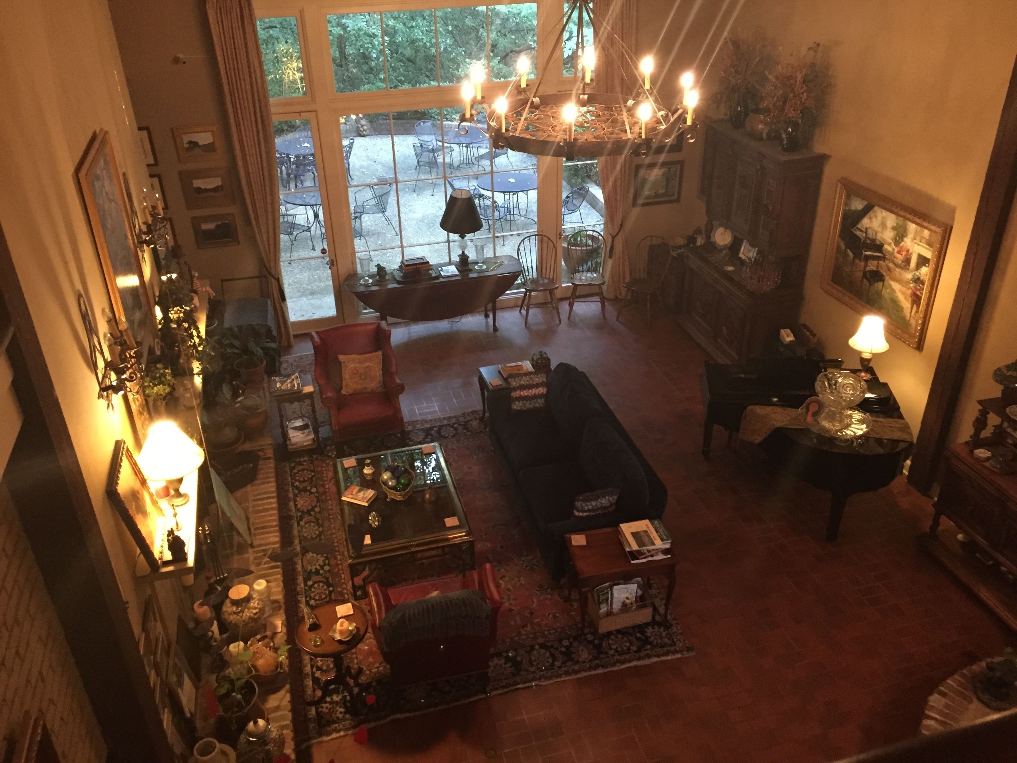 A cozy living room with a fireplace, a dining area with outdoor seating, and a large window overlooking a garden.