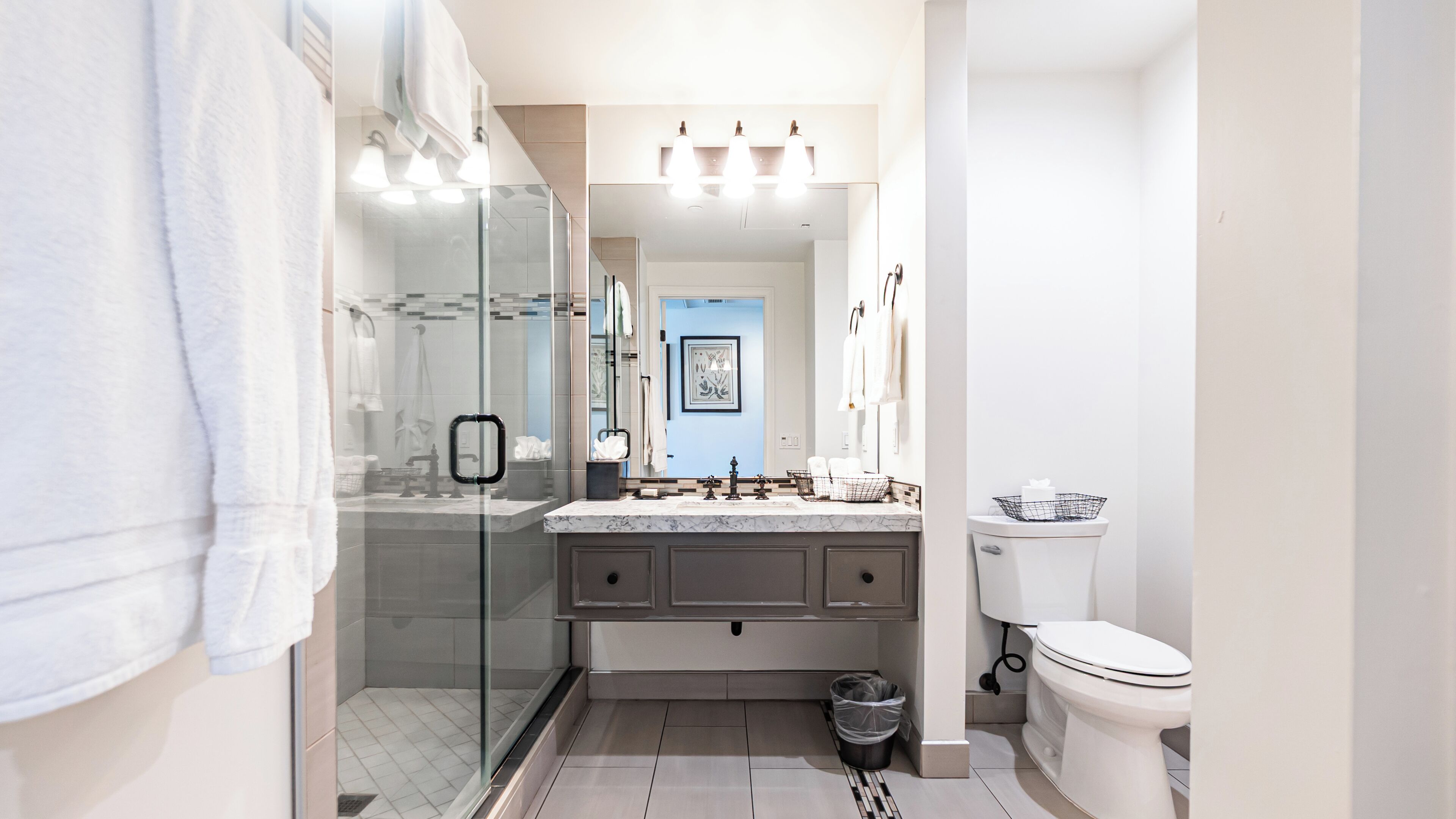 A modern bathroom with a glass shower enclosure, a marble countertop, and a toilet.