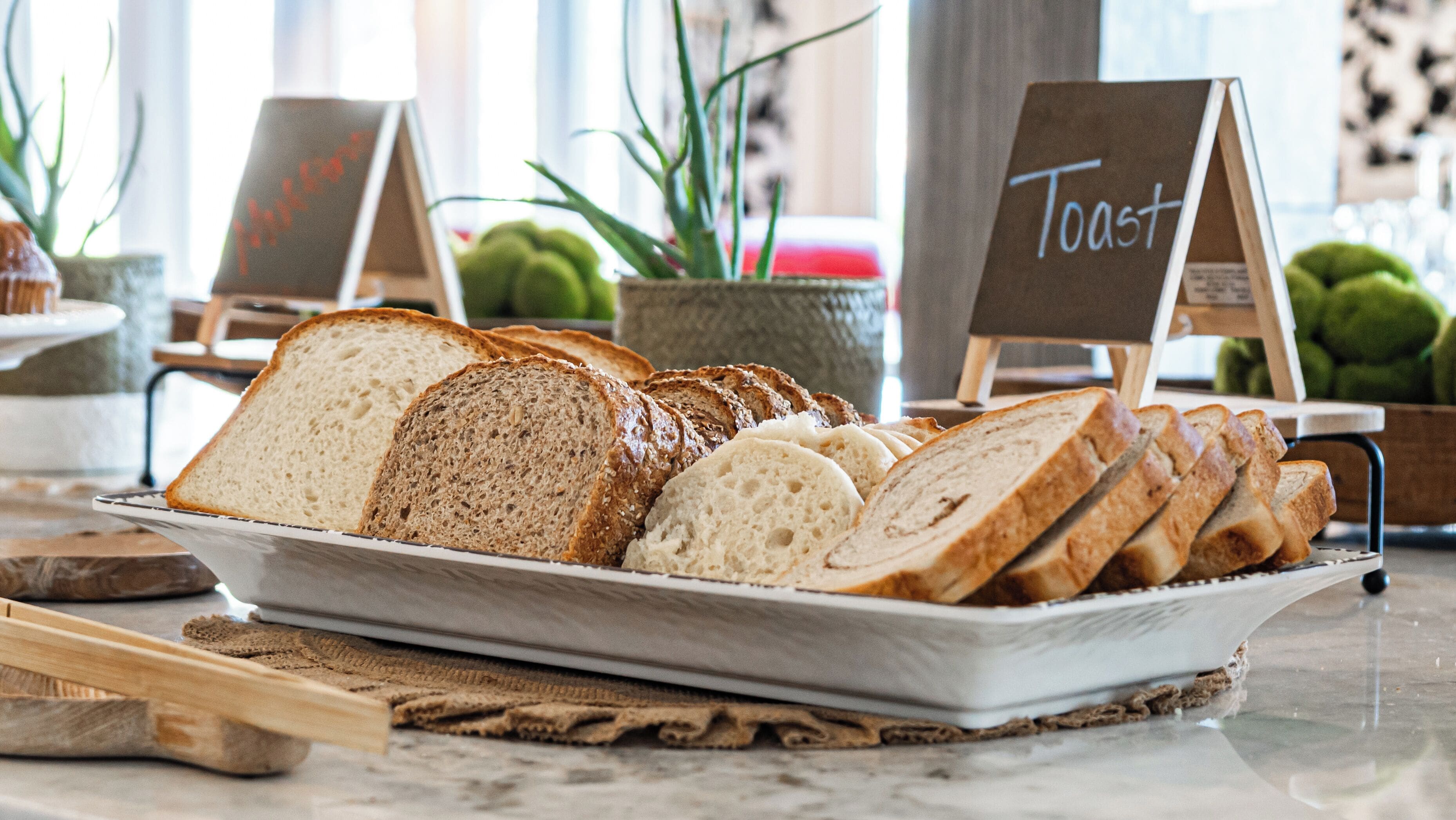 A variety of sliced breads on a tray with a sign that reads "Toast".