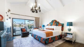 A spacious bedroom with a large bed, a chandelier, a nightstand, and a view of a body of water.