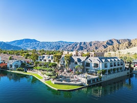 Un resort con piscina, palmeras y montañas al fondo.