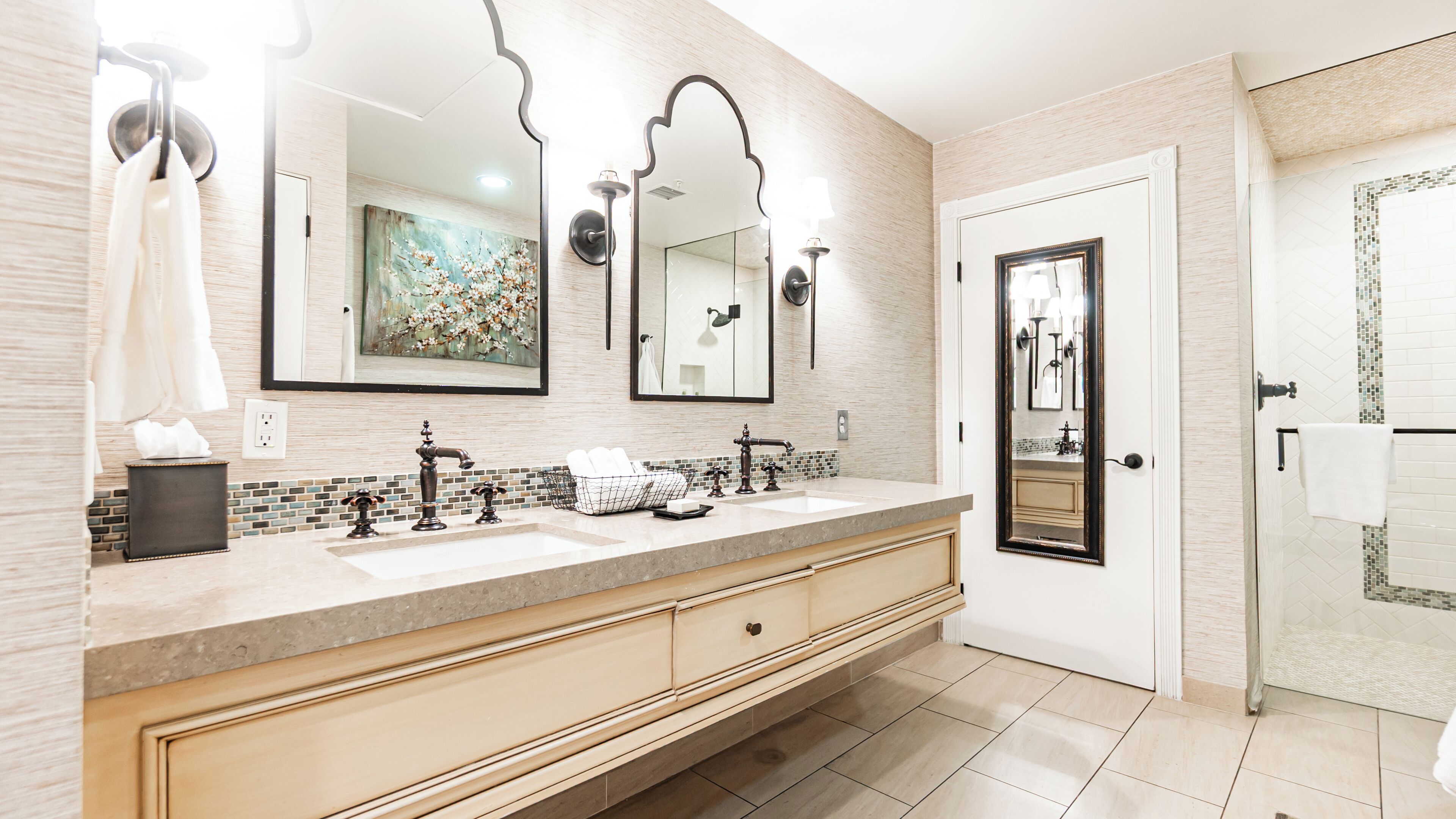 A modern bathroom with a large mirror, two sinks, and a shower area.
