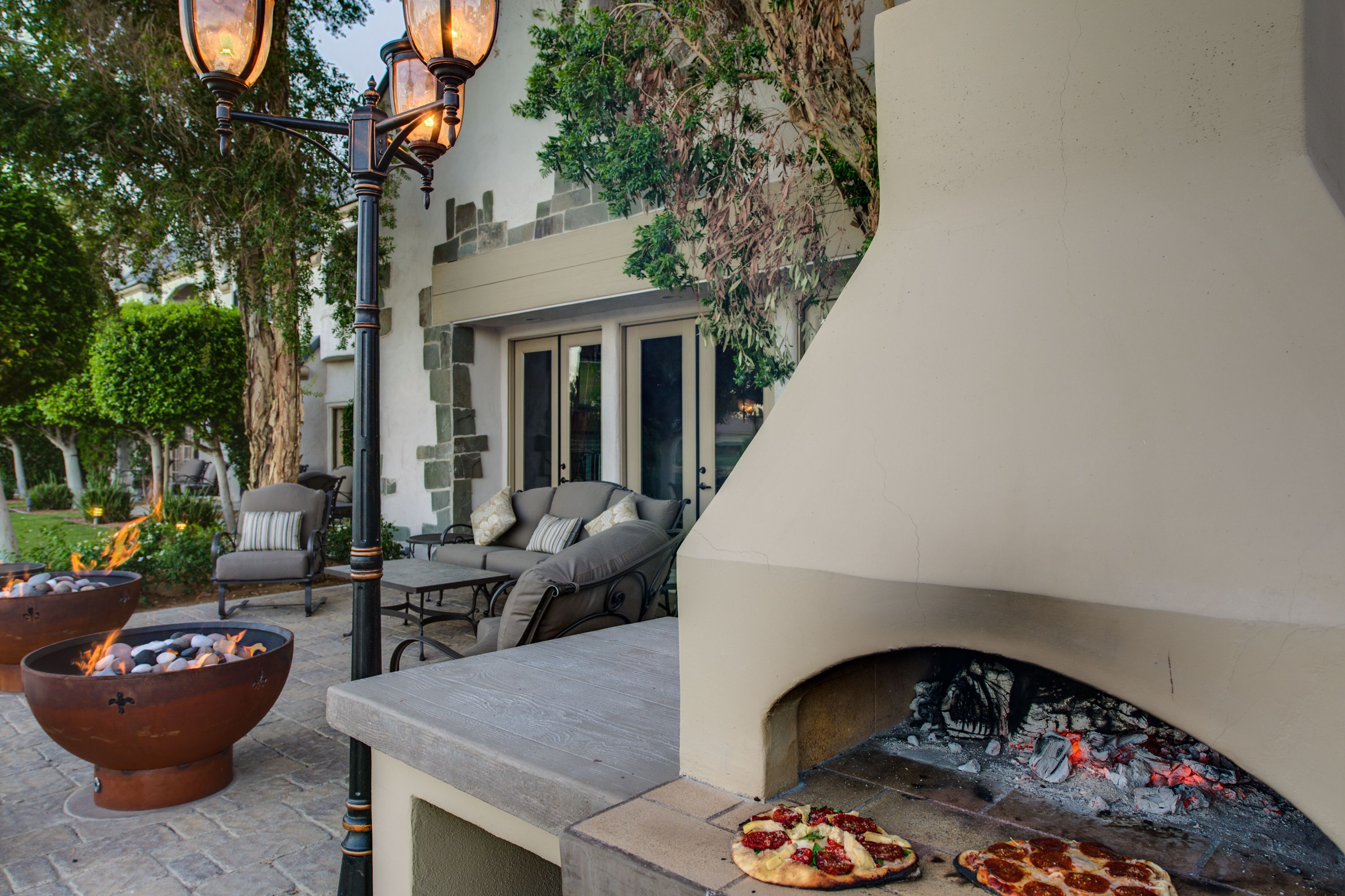 Une terrasse extérieure dotée d’une cheminée en pierre, d’un espace salon et de foyers.