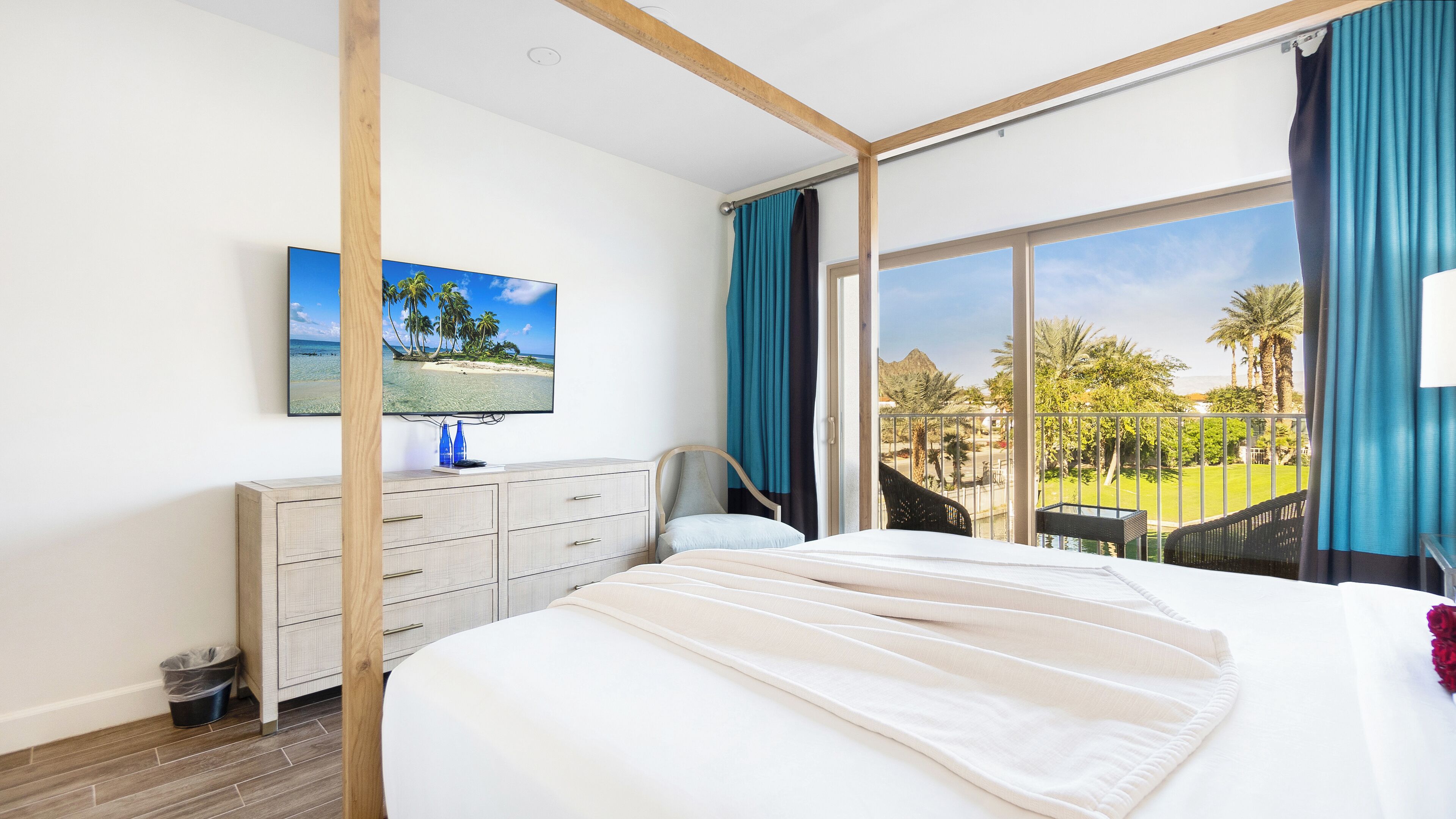 Une chambre d’hôtel avec un lit, un téléviseur fixé au mur, un bureau avec des tiroirs et une vue sur l’extérieur.