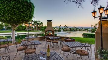 Relax in a serene setting surrounded by a small pond and landscaped garden, with seating options and a central fire feature.