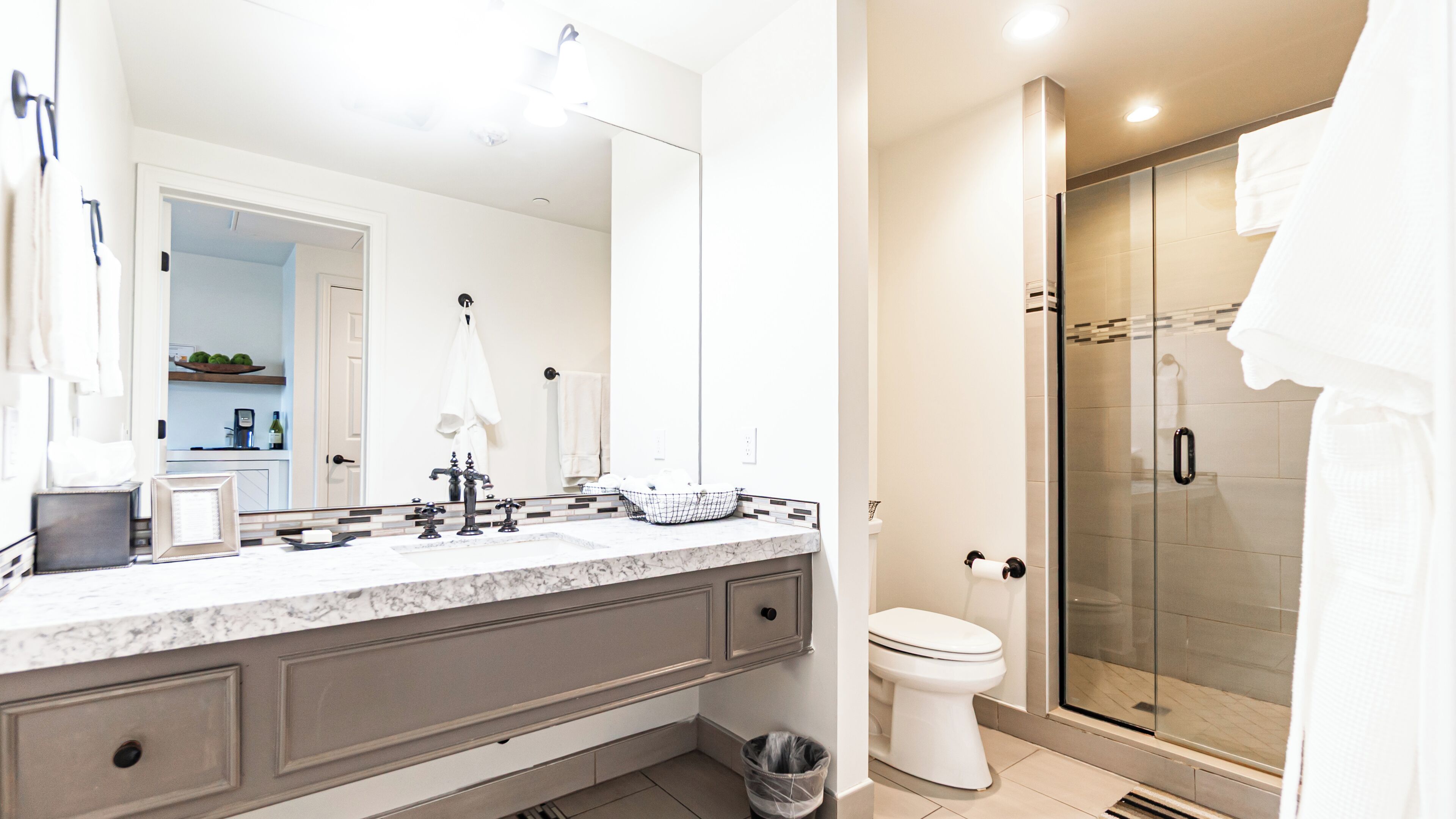 Een moderne badkamer met een marmeren wastafelmeubel, een douchecabine van glas en een toilet.