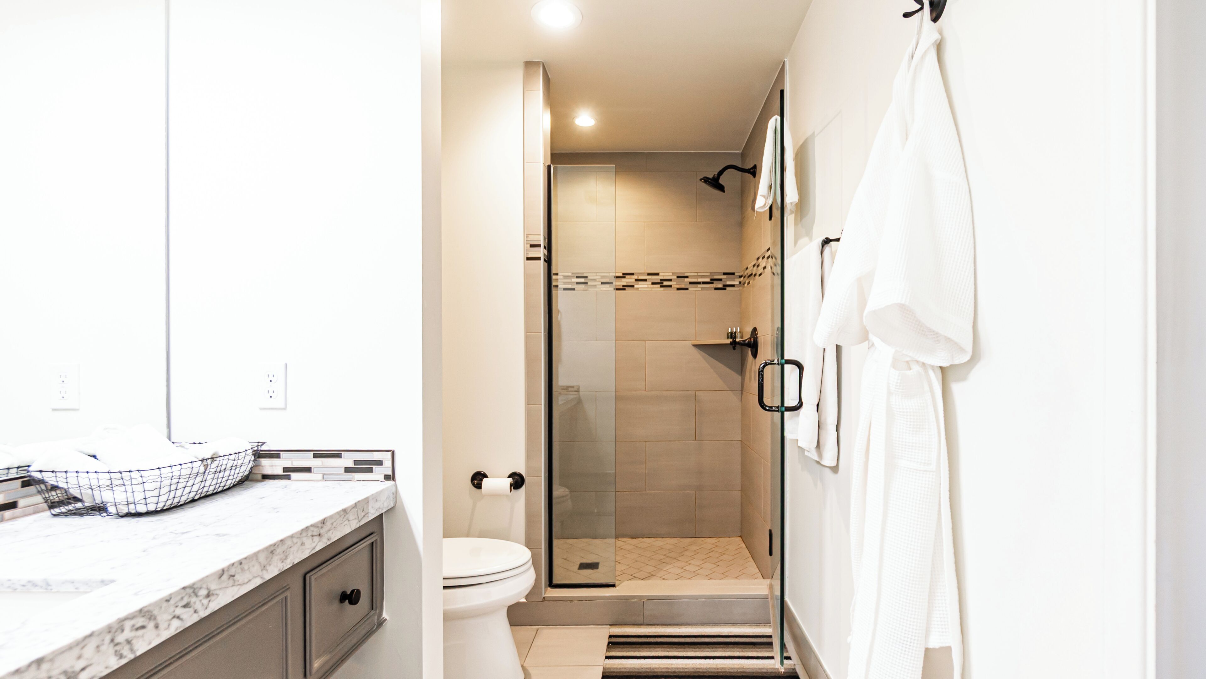 Een moderne badkamer met een douche, toilet en een marmeren aanrecht.