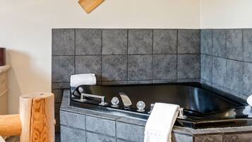 Un bagno moderno con una vasca da bagno nera, un remo di legno e un asciugamano appeso al muro.