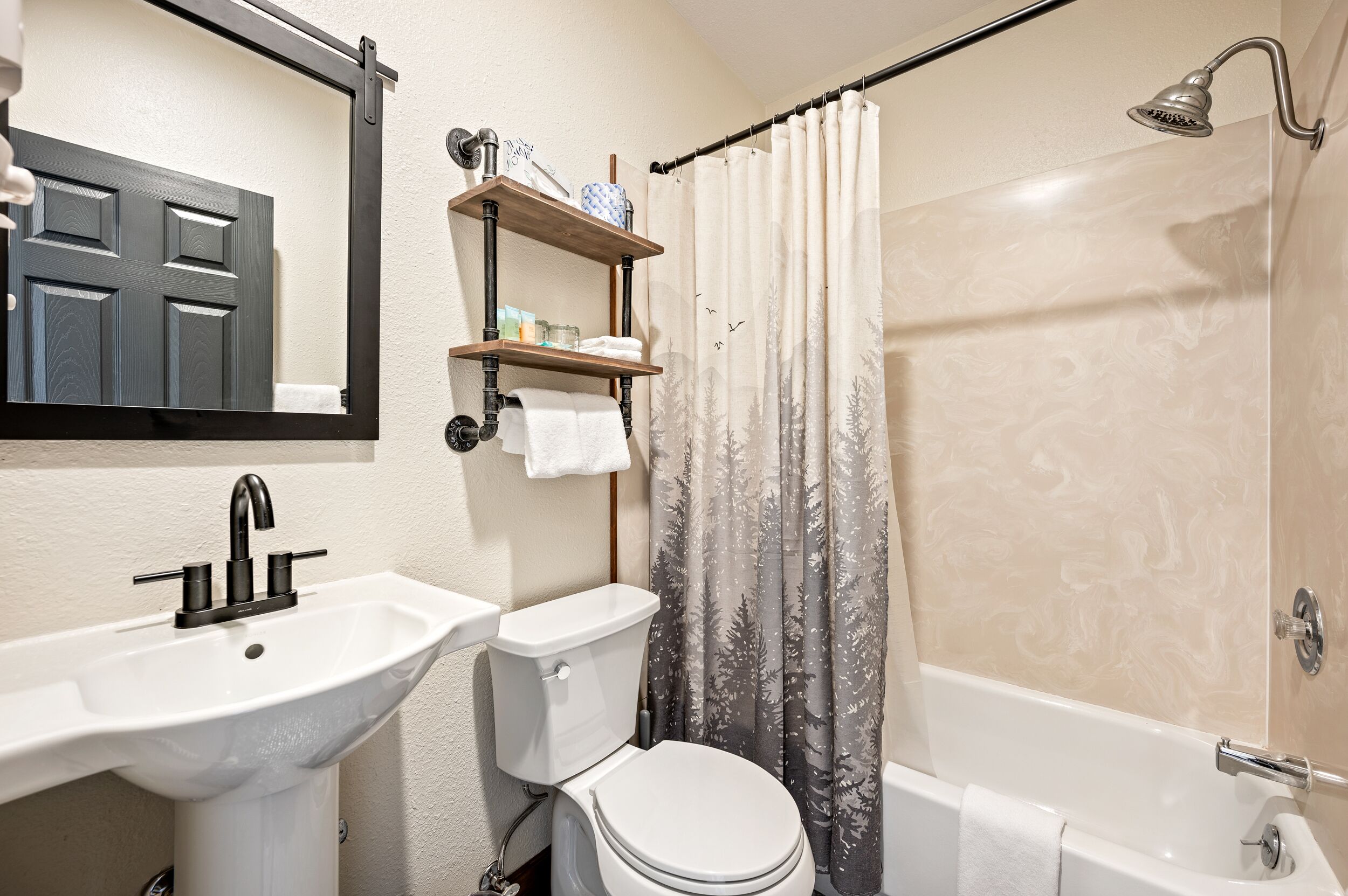 A bathroom with a sink, toilet, and bathtub. There is a shelf above the toilet with toiletries.