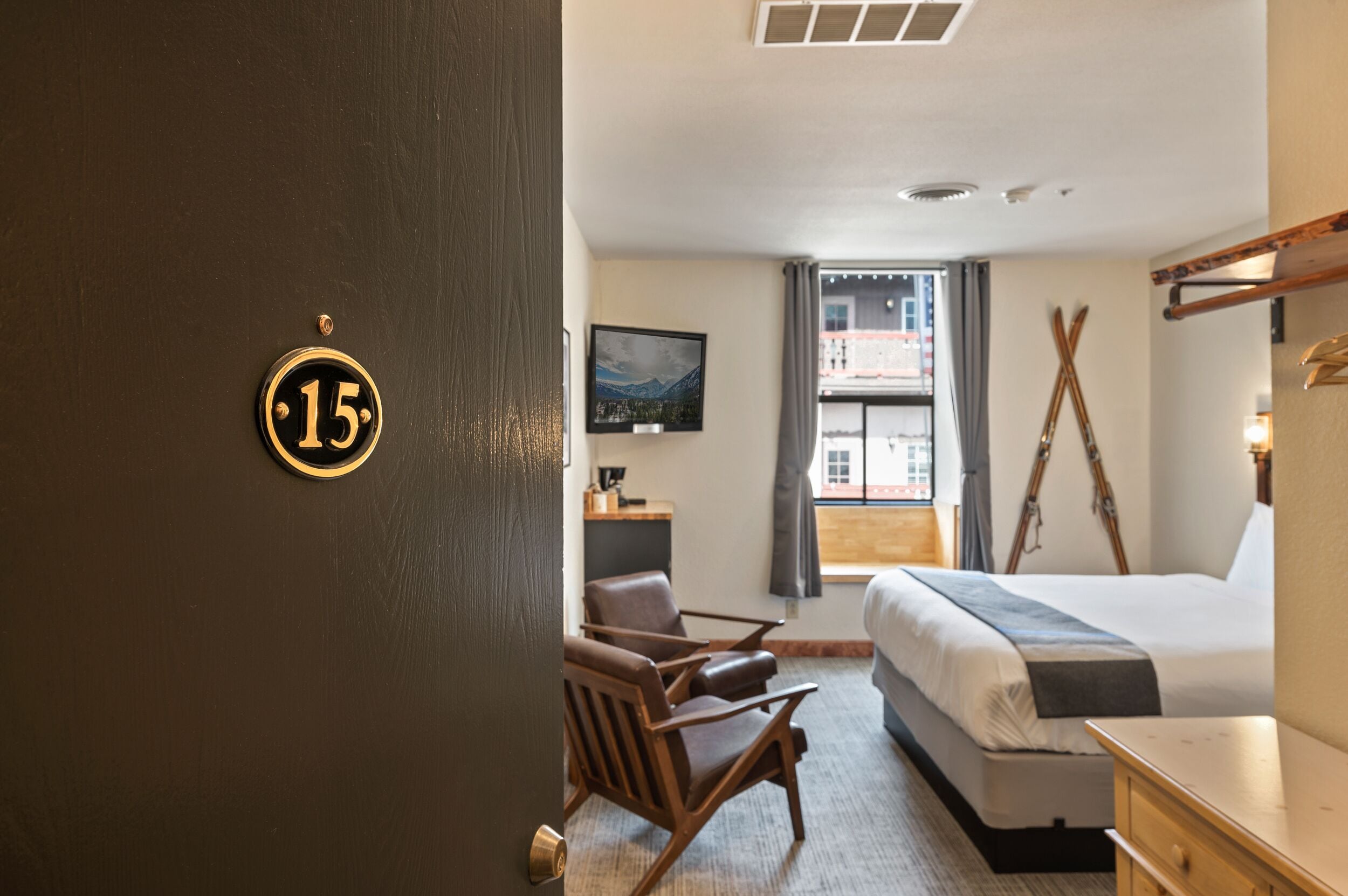 Habitación de hotel con cama, escritorio, silla y ventana con vista a un edificio.