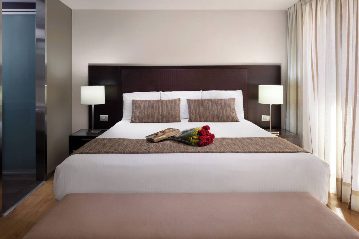 A hotel room with a large bed, two bedside tables, and a nightstand.