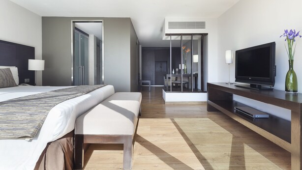 A modern hotel room with a large bed, a TV, a desk, and a dining area. - Exe Suites Reforma (Mexico City)