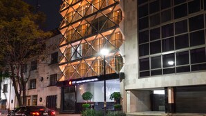 A modern hotel with a unique geometric facade, large windows, and a visible entrance with a sign. - Exe Suites Reforma (Mexico City)