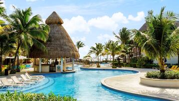 Alberca al aire libre, sombrillas en la alberca y camastros