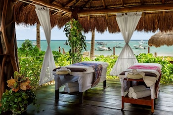 A beachside hotel with rows of sun loungers and umbrellas, palm trees, and a clear sky. at The Reef Coco Beach Resort & Spa- Optional All Inclusive