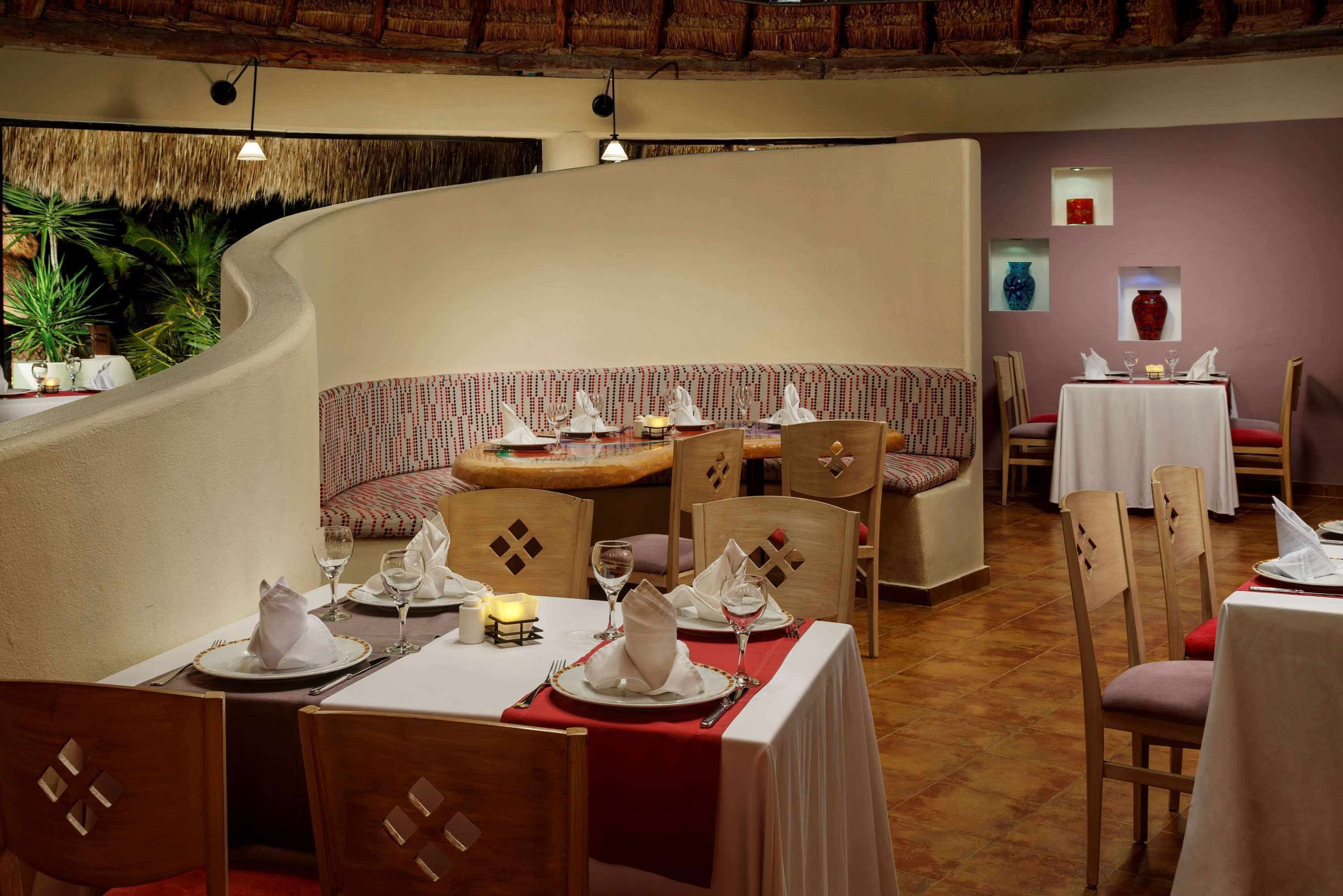 Ein Restaurant mit einer gewölbten Wand, Holzsesseln und gedeckten Tischen.