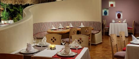 Un restaurante con pared curva, sillas y mesas de madera dispuestas para comer.