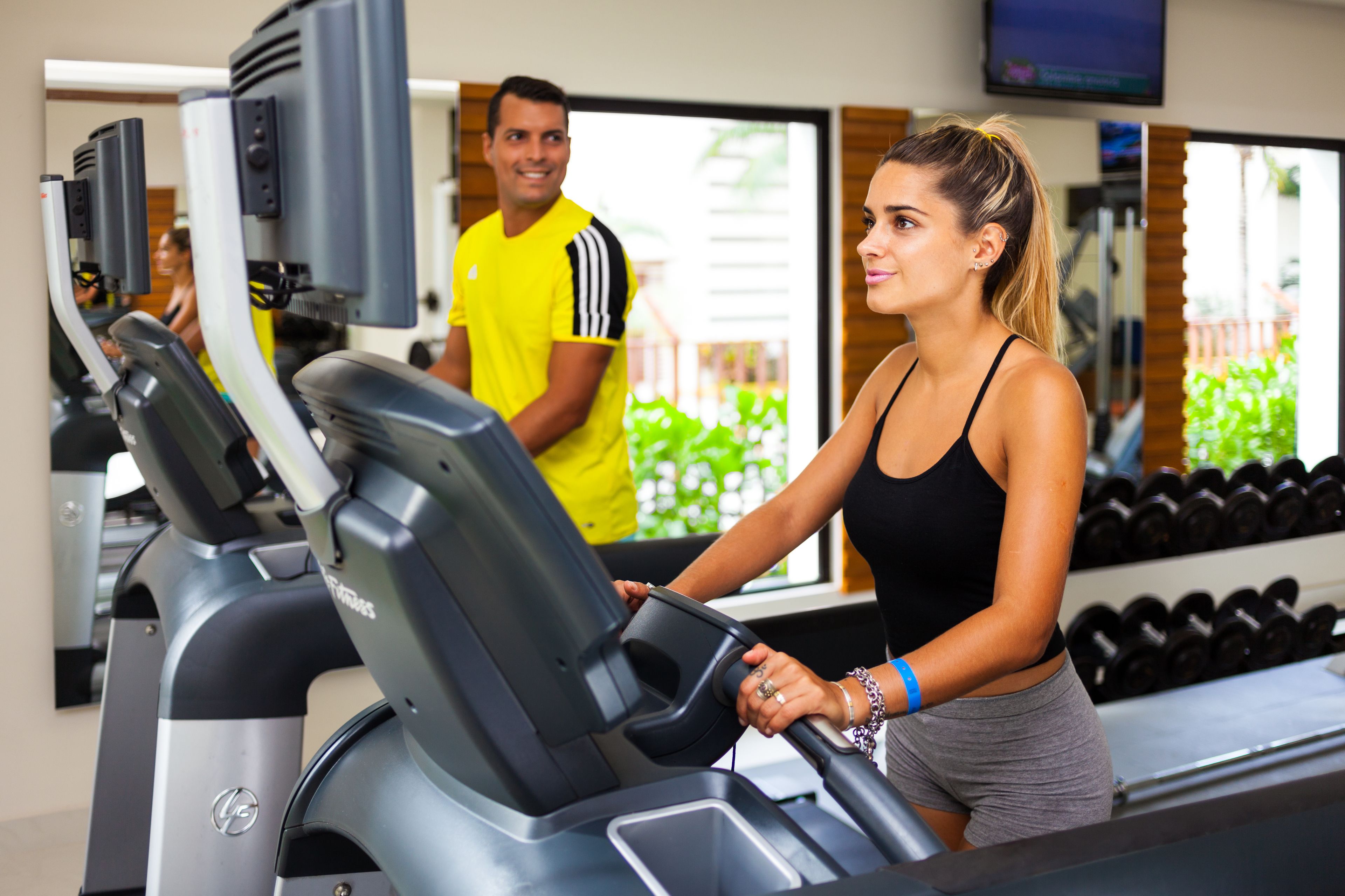 Une salle de sport équipée de tapis de course et d’haltères.