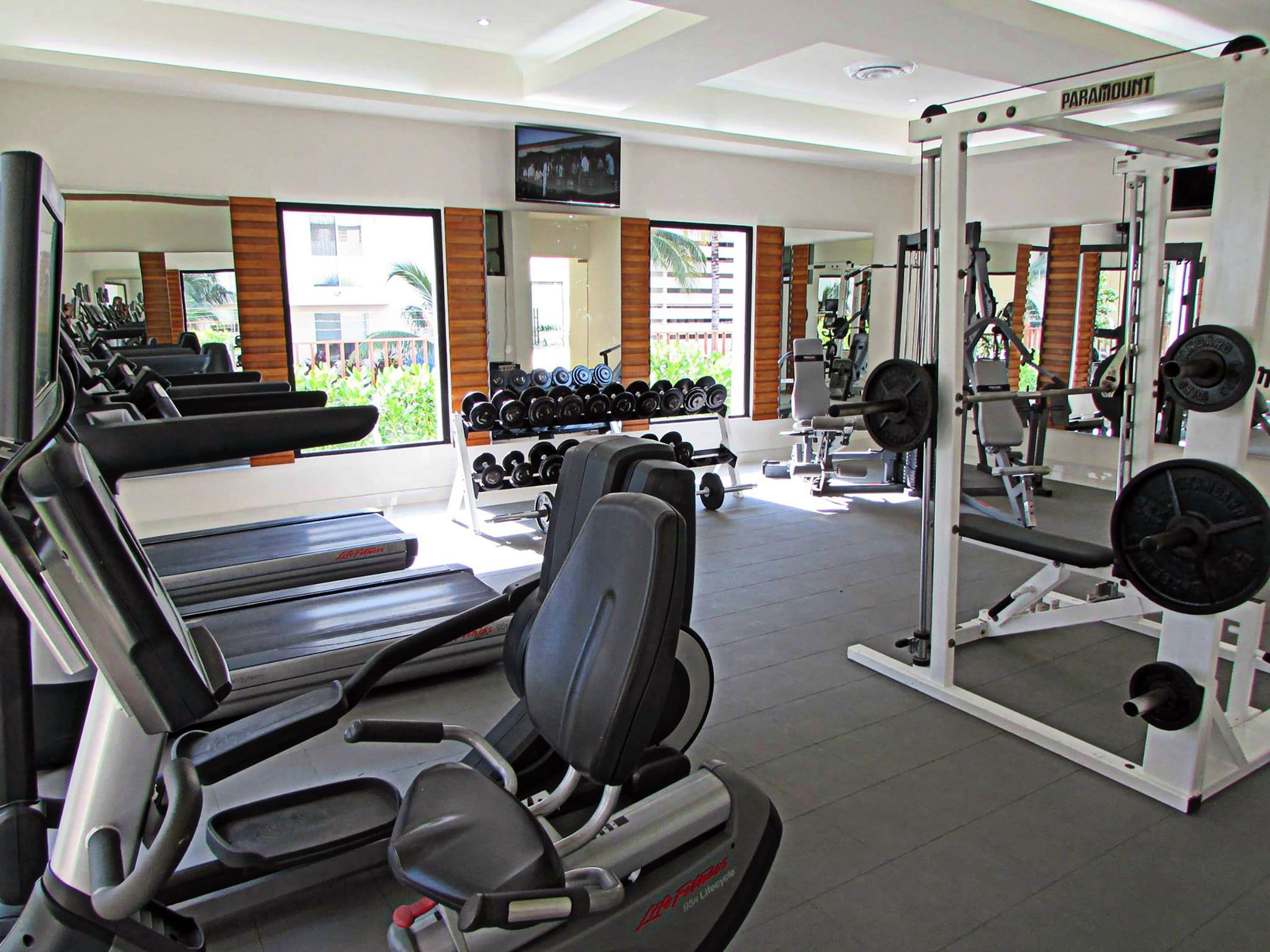 A gym with treadmills, weight machines, and dumbbells.
