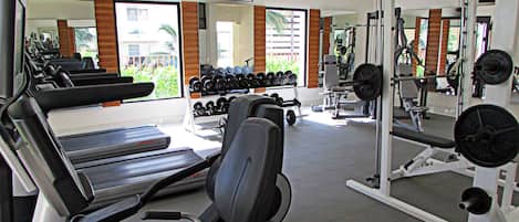 A gym with treadmills, weight machines, and dumbbells.