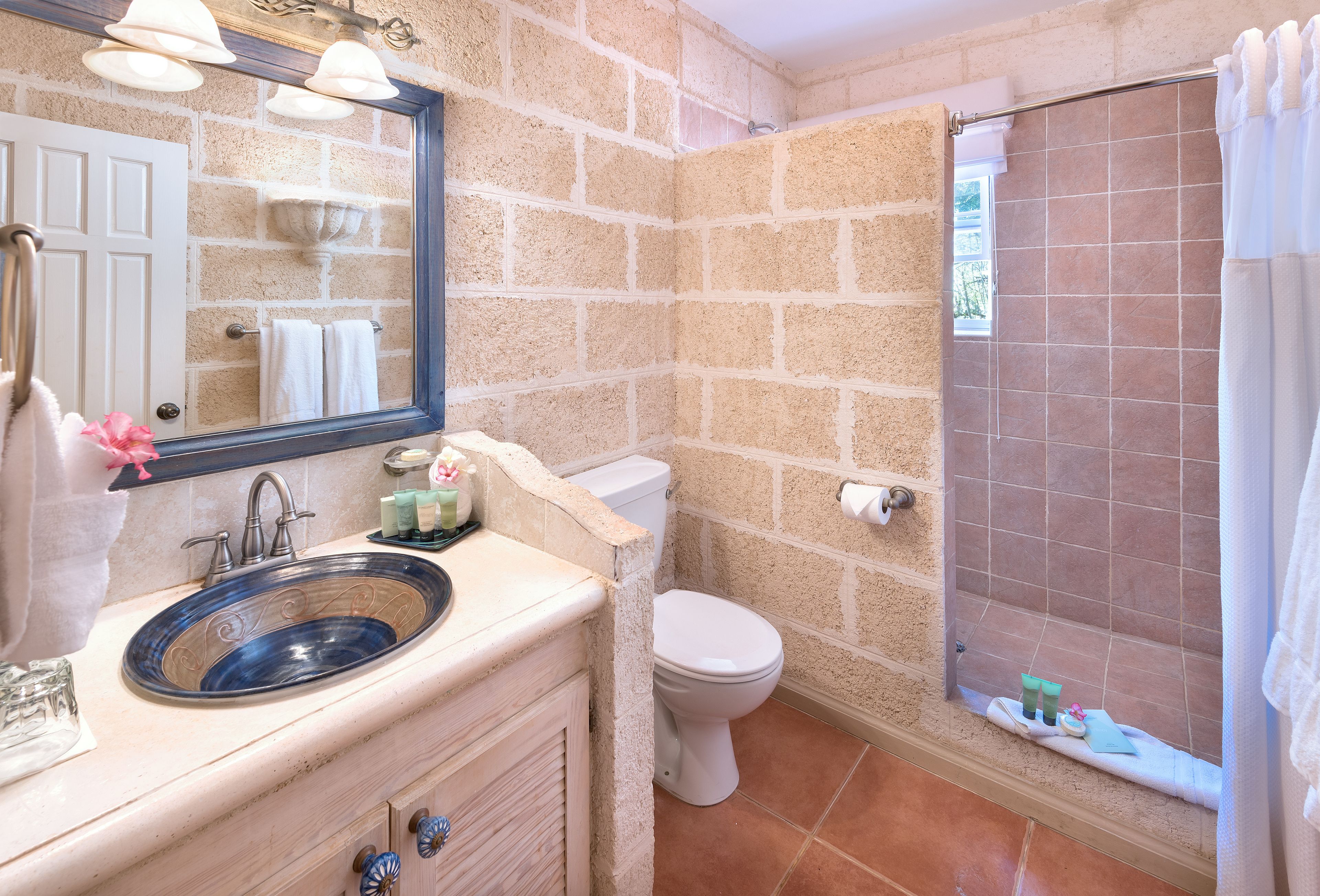 A bathroom with a sink, mirror, toilet, and shower.