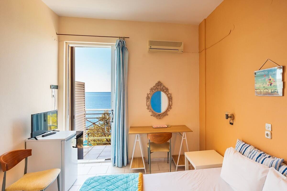 Ein Hotelzimmer mit Bett, Schreibtisch, Stuhl und Meerblick vom Balkon.