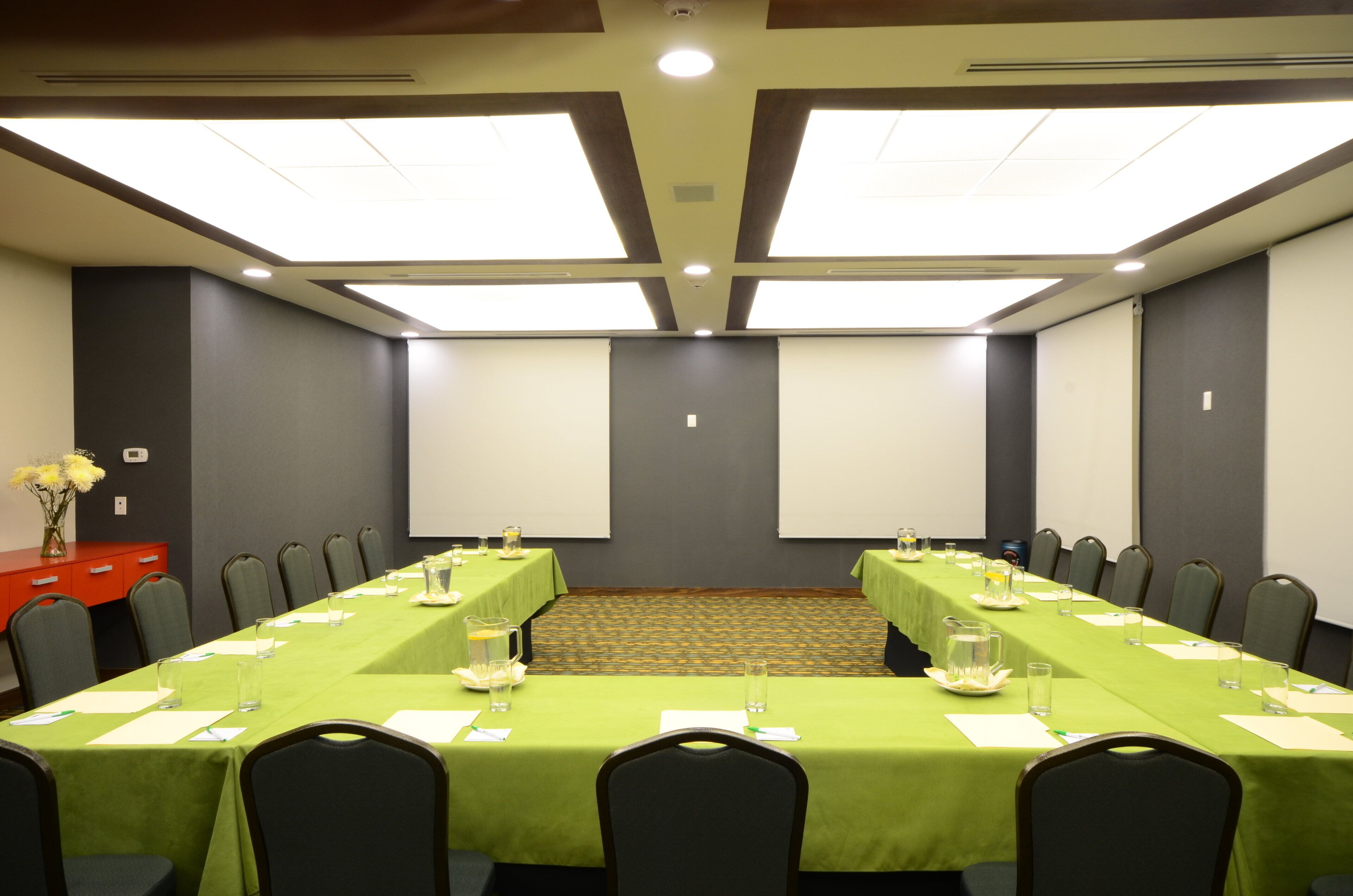 A conference room with a long table, chairs, and a projector screen.