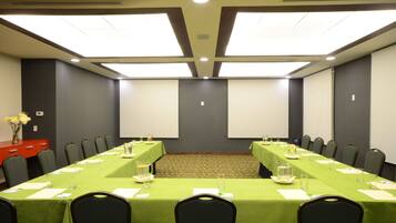 A conference room with a long table, chairs, and a projector screen.