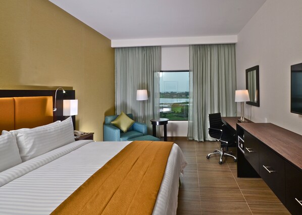 Quarto de hotel com uma cama grande, uma escrivaninha, uma cadeira e vista para a água.