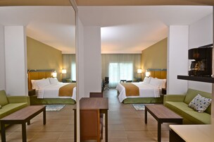 Habitación de hotel con dos camas, un sofá, una cafetera y un televisor.