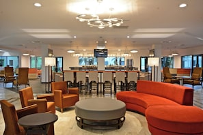 A modern hotel lobby with a bar area, seating arrangements, and a large screen. - Holiday Inn Tampico Altamira by IHG (Altamira)