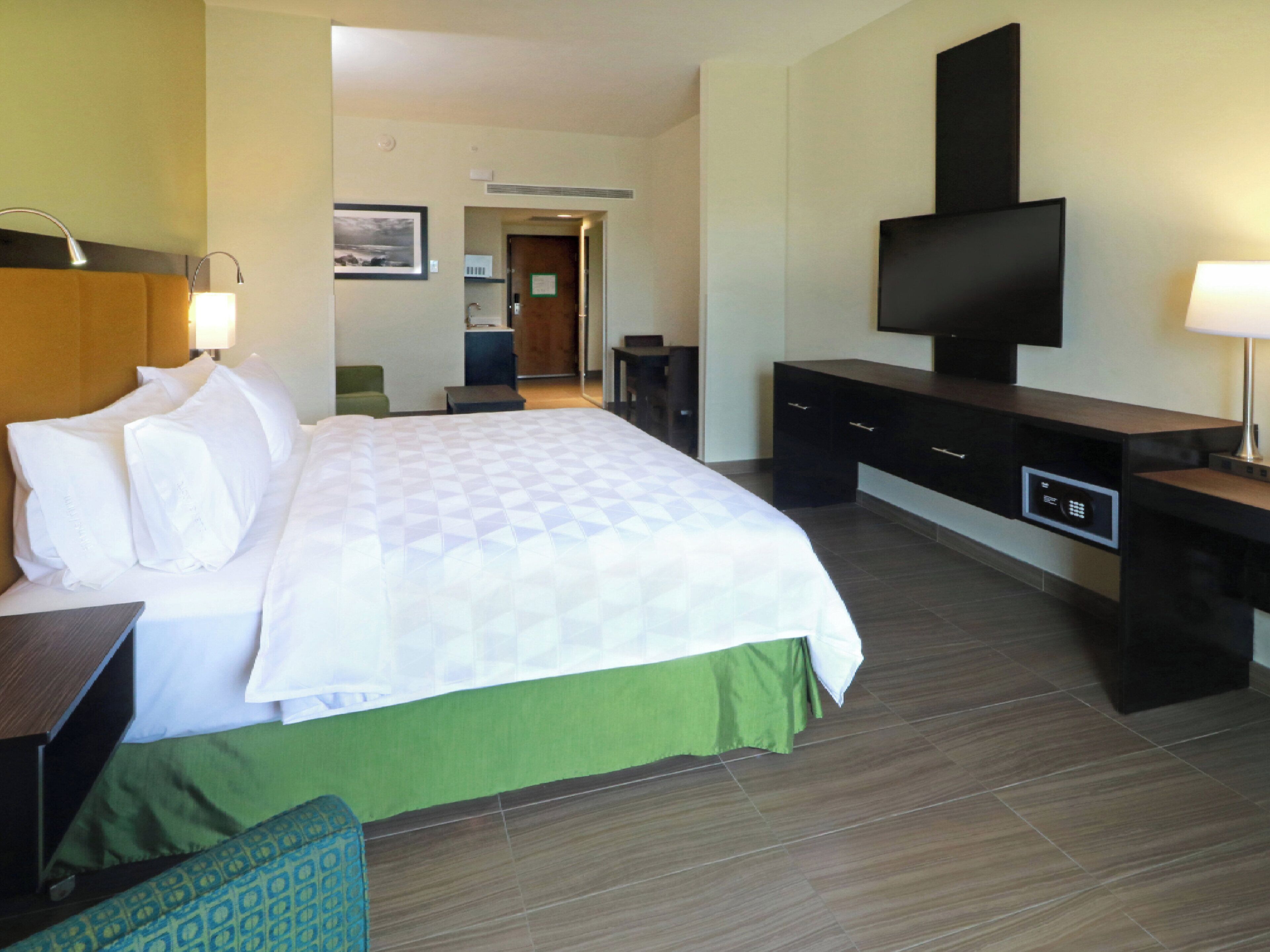 Quarto de hotel com uma cama, televisão, escrivaninha e cadeira.