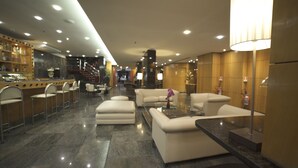 A modern lobby with a bar area, seating, and a staircase.