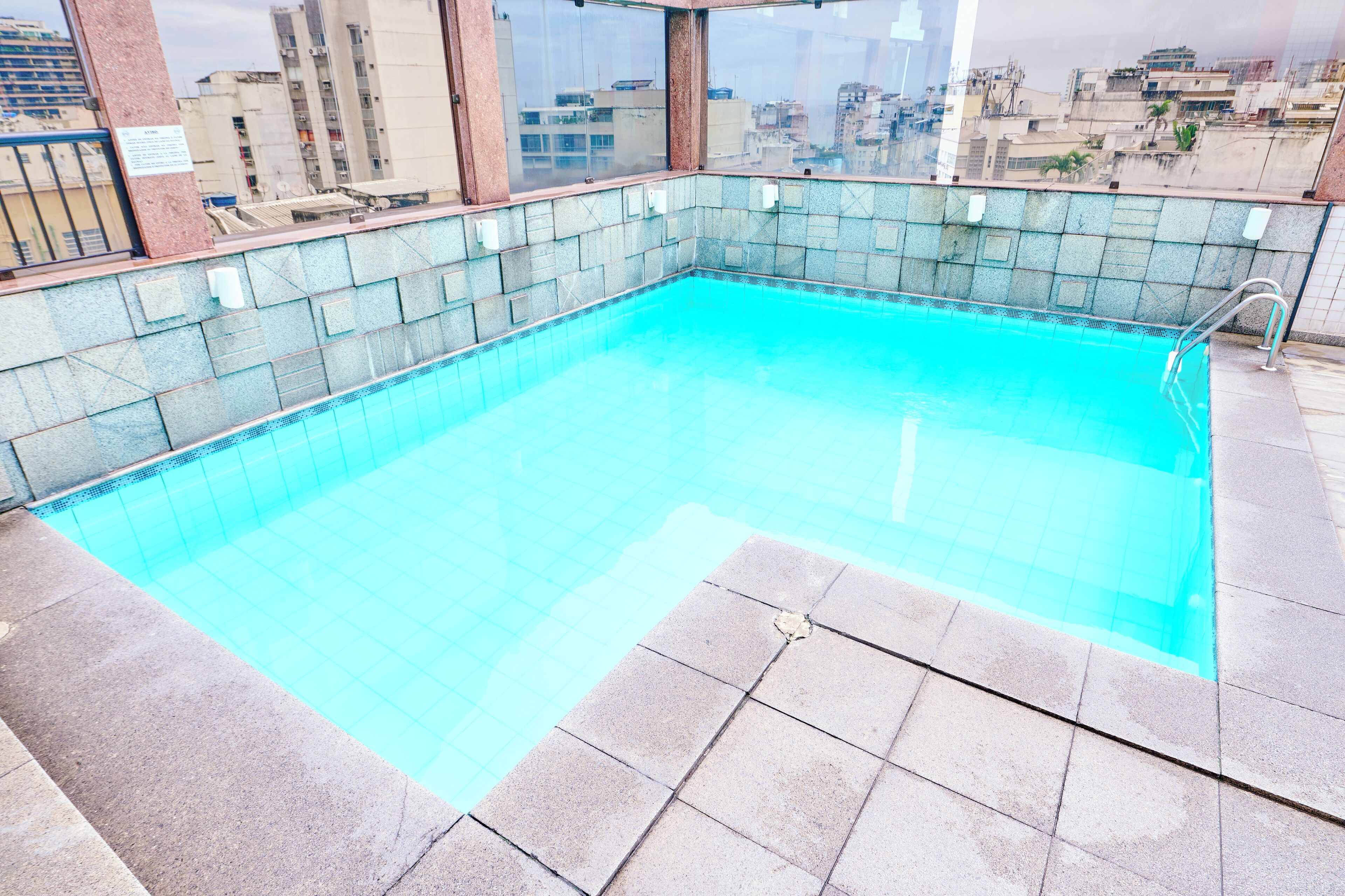 A rooftop swimming pool with tiled walls and a clear blue pool.