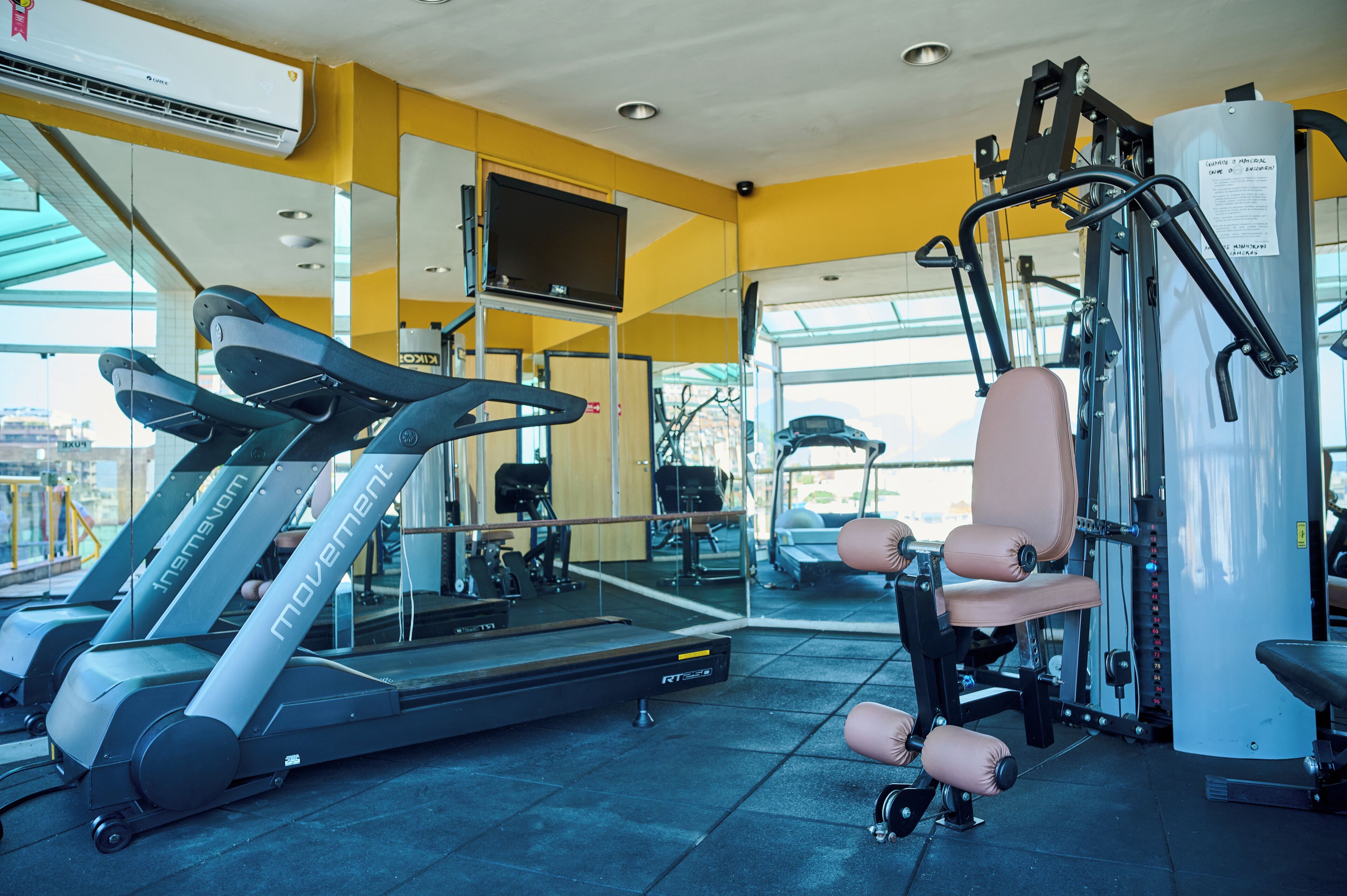 Un gimnasio con cintas de correr, máquinas de pesas y un muro de espejos.
