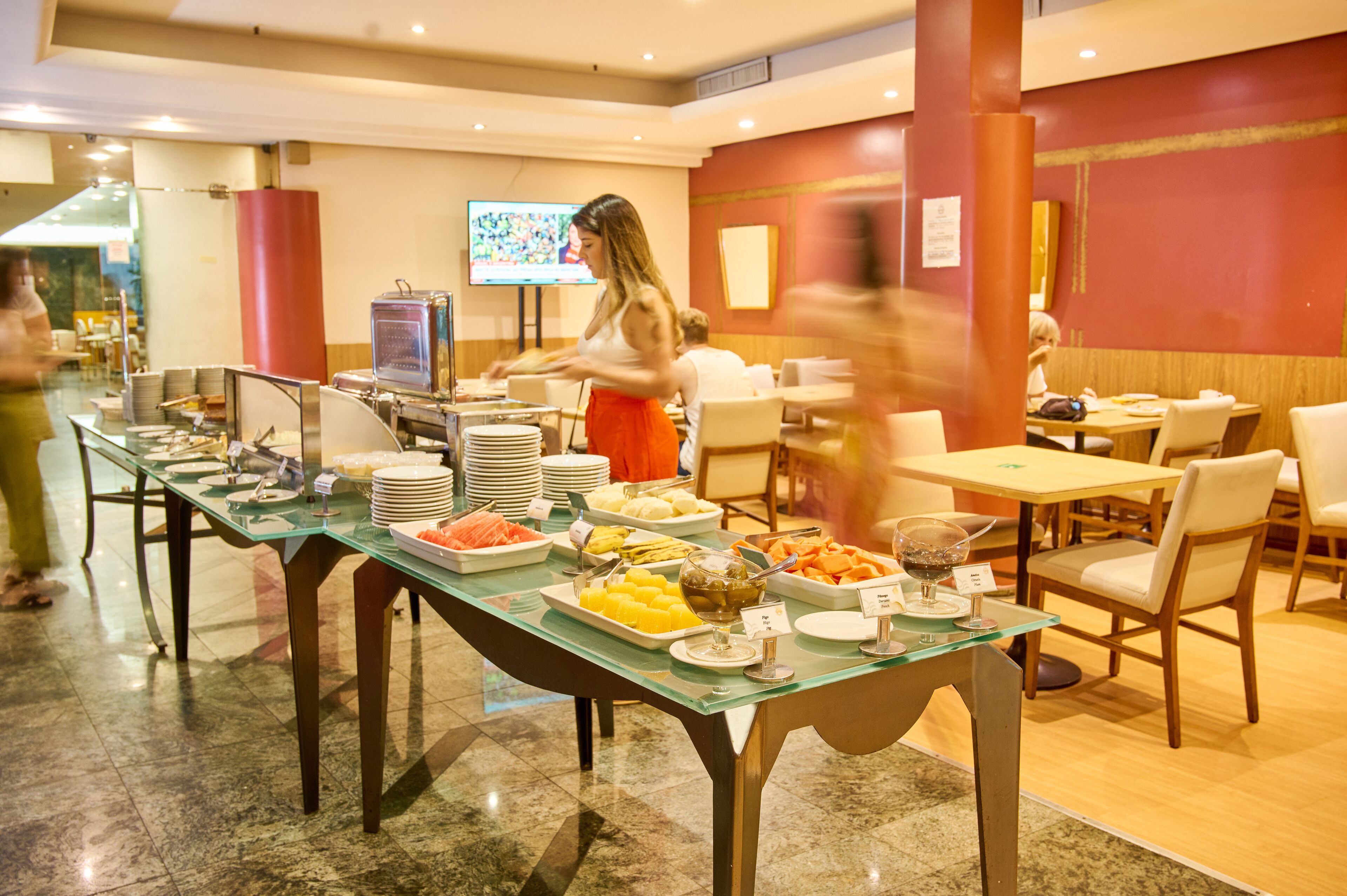 A buffet setup with various food items and a television screen in the background.