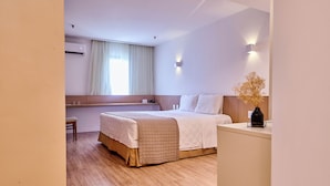 A hotel room with a bed, a desk, and a window with curtains.