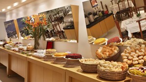 A buffet table with various food items and a vase of flowers. - Copa Sul Hotel (Rio de Janeiro)